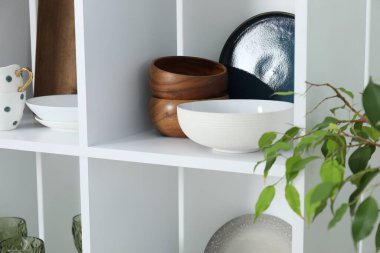 İçerideki raflarda farklı temiz bulaşık takımları ve bardaklar var.