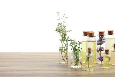 Beyaz arka plana karşı ahşap masa üzerinde gerekli yağlar ve farklı otlar.