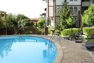 Lüks otellerde açık yüzme havuzu, güneşli yataklar ve yeşil bitkiler