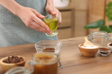 Doğal temizlik yapıyorum. Ahşap masada yağlı boya katan kadın, yakından.