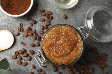 Cam kavanozda doğal vücut fırçası ve gri masada bulunan malzemeler.