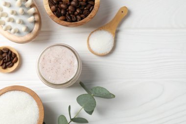 Doğal vücut fırçası cam kavanozda, malzemeler beyaz ahşap masada, düz yerde. Metin için boşluk