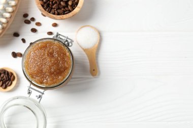 Doğal vücut fırçası cam kavanozda, malzemeler beyaz ahşap masada, düz yerde. Metin için boşluk