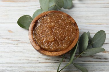 Doğal vücut fırçası kasede ve okaliptüs dalları ahşap masada, görünümün üstünde.