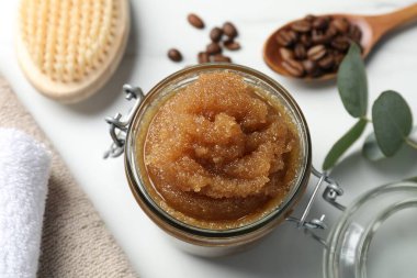 Doğal vücut fırçası, kahve çekirdekleri ve okaliptüs yaprakları beyaz masanın üstünde.