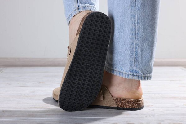 Женщина в стильных бежевых тапочках на светлом деревянном полу, крупным планом