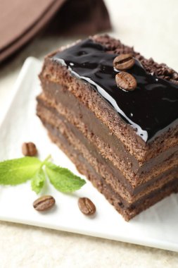 Bir parça çikolatalı kek, beyaz masada nane şekeri ile servis ediliyor, yakın plan.