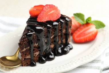 Çilek ve kaşıkla servis edilen bir parça çikolatalı pasta.