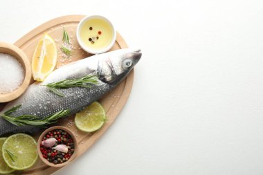 Beyaz masadaki baharatlı taze çiğ deniz kabuğu balığı, üst manzara ve yazı için yer. Deniz ürünleri lezzetleri.