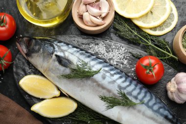 Taze çiğ uskumru ve baharatlar siyah masada, düz yerde. Deniz ürünleri lezzetleri.