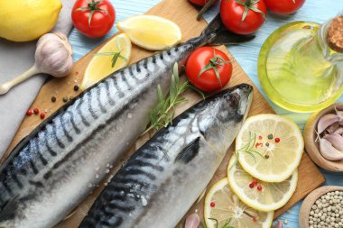 Taze çiğ uskumrular ve baharatlar açık mavi ahşap masada, düz yerde. Deniz ürünleri lezzetleri.