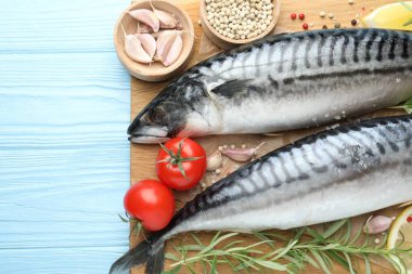 Deniz ürünleri lezzetleri. Taze çiğ uskumrular ve baharatlar açık mavi ahşap masada, düz yerde. Metin için boşluk