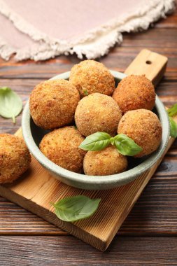 Tahta masadaki fesleğende fesleğen olan lezzetli kızarmış kroket topları, yakın plan.