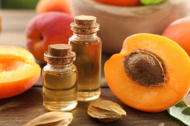 Şişelerdeki, tohumlardaki ve olgun kayısılardaki yağlar ahşap masada, yakın plan.