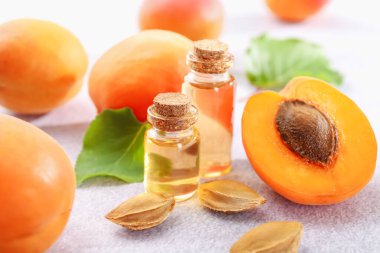 Şişelerdeki, tohumlardaki ve olgun kayısılardaki yağlar açık dokulu masalarda, yakın çekim.