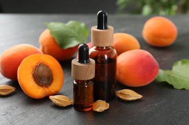 Şişelerde, tohumlarda ve olgun kayısılarda koyu dokulu masalarda, yakın çekim.