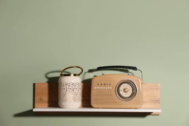 Açık yeşil duvarda lamba ve radyo alıcısı olan beyaz ahşap raf, metin için alan