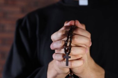 Bulanık arka planda tespih çeken rahip, yakın plan.