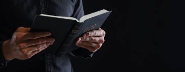 Siyah arka planda İncil 'i olan bir rahip, yakın plan. Metin için boşluk