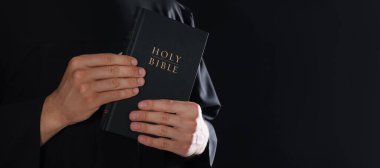 Siyah arka planda İncil 'i olan bir rahip, yakın plan. Metin için boşluk