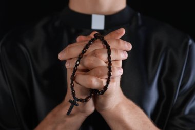 Siyah arka planda tespih çeken rahip, yakın plan.