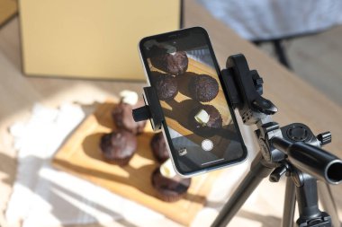 Stüdyoda akıllı telefonla çikolatalı kek çekmek, yakın çekim. Profesyonel yemek fotoğrafçılığı.