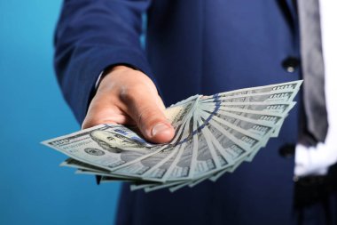 Mavi arka planda dolar banknotları olan adam, yakın plan.