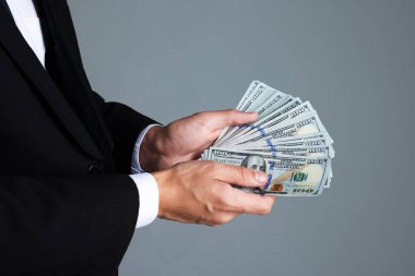 Gri arka planda dolar banknotları olan adam, yakın plan.