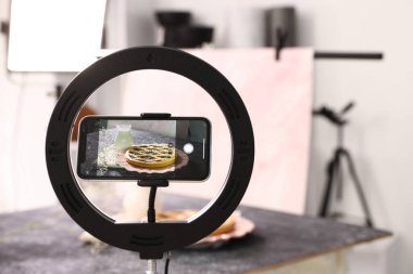 Stüdyoda akıllı telefonlu lezzetli turta ve süt çekmek, seçici odaklanma. Profesyonel yemek fotoğrafçılığı.