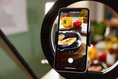 Stüdyoda lezzetli kızarmış balık ve akıllı telefonlu malzemeler çekmek, seçici odaklanma. Profesyonel yemek fotoğrafçılığı.