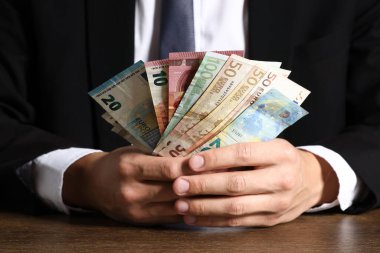Tahta masada Euro banknotları olan adam, yakın plan.