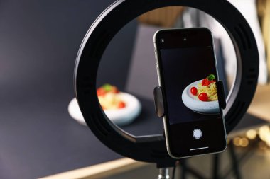 Stüdyoda akıllı telefonla lezzetli makarna çekmek, ekrana odaklanmak. Profesyonel yemek fotoğrafçılığı.