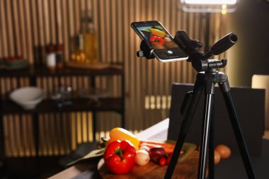 Stüdyoda akıllı telefonla sebze vurmak, seçici bir odak noktası. Profesyonel yemek fotoğrafçılığı.