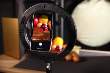 Stüdyoda akıllı telefonla sebze çekmek, ekrana odaklanmak. Profesyonel yemek fotoğrafçılığı.