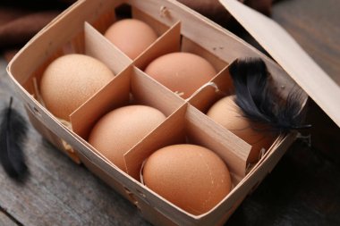 Yumurta tepsisindeki çiğ tavuk yumurtaları ahşap masada, yakın plan.