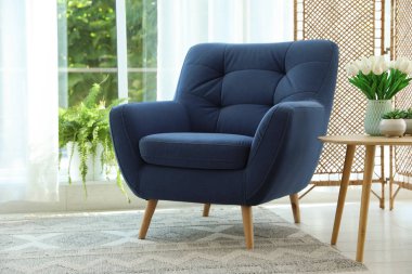 Pencerenin yanında, içinde perdeler olan şık bir mavi koltuk. İç tasarım