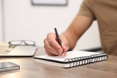 Metin yazarı deftere yazıyor, ahşap masa içinde, yakın plan.