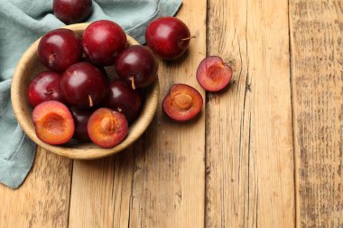 Olgun kiraz erikleri, kase ve kumaş ahşap masada, düz bir şekilde yatıyordu. Metin için boşluk
