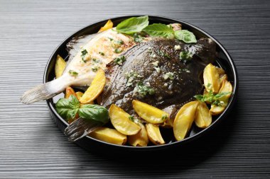 Siyah masada otlu ve patatesli kızarmış balık, yakın plan. Ev yapımı deniz ürünleri yemeği.