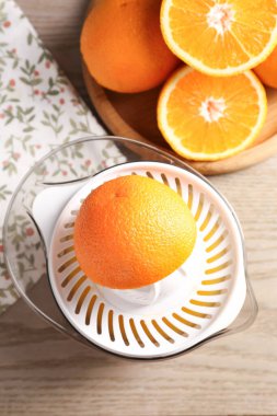 Meyve suyu. Meyve sıkacağı ve taze portakallar ahşap masada, düz yatıyordu.