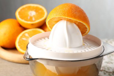 Meyve suyu. Meyve sıkacağı ve taze portakallar masada, yakın plan.