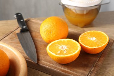 Meyve suyu. Taze portakallar, meyve sıkacağı ve bıçak ahşap masada, yakın plan.