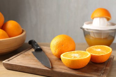 Meyve suyu. Meyve sıkacağı, taze portakal ve bıçak ahşap masada, yakın plan.