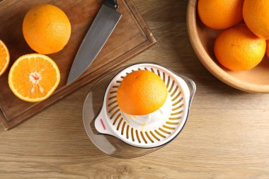 Meyve suyu. Meyve sıkacağı, taze portakal ve bıçak ahşap masada, düz yerde.