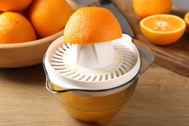 Meyve suyu. Meyve sıkacağı, taze portakal ve bıçak ahşap masada, yakın plan.