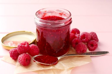 Cam kavanozda tatlı ahududu reçeli ve pembe ahşap masada böğürtlen, yakın plan.