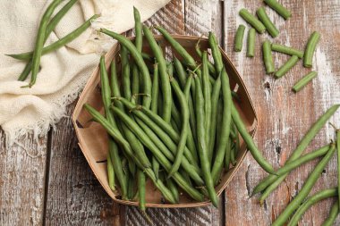 Taze bezelye kabukları, sepet ve kumaş renkli ahşap masa, düz uzanma