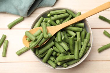 Taze bezelye kabukları kasede ve kaşıklar açık ahşap masada, düz yatıyordu.