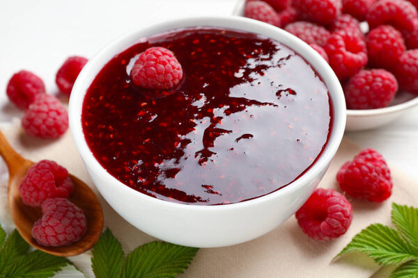 Сладкое малиновое варенье в миске и ягоды на столе, крупным планом