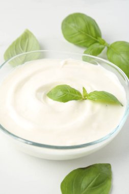 Lezzetli yoğurt ve fesleğen beyaz masada, yakın plan.